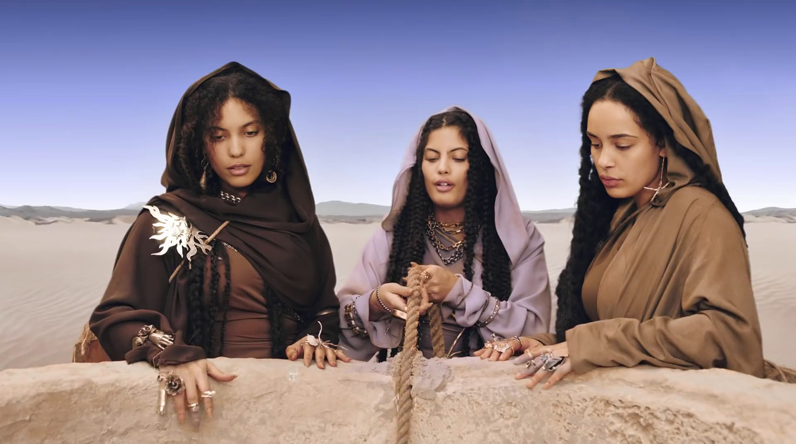 three women dressed in brown are looking at something