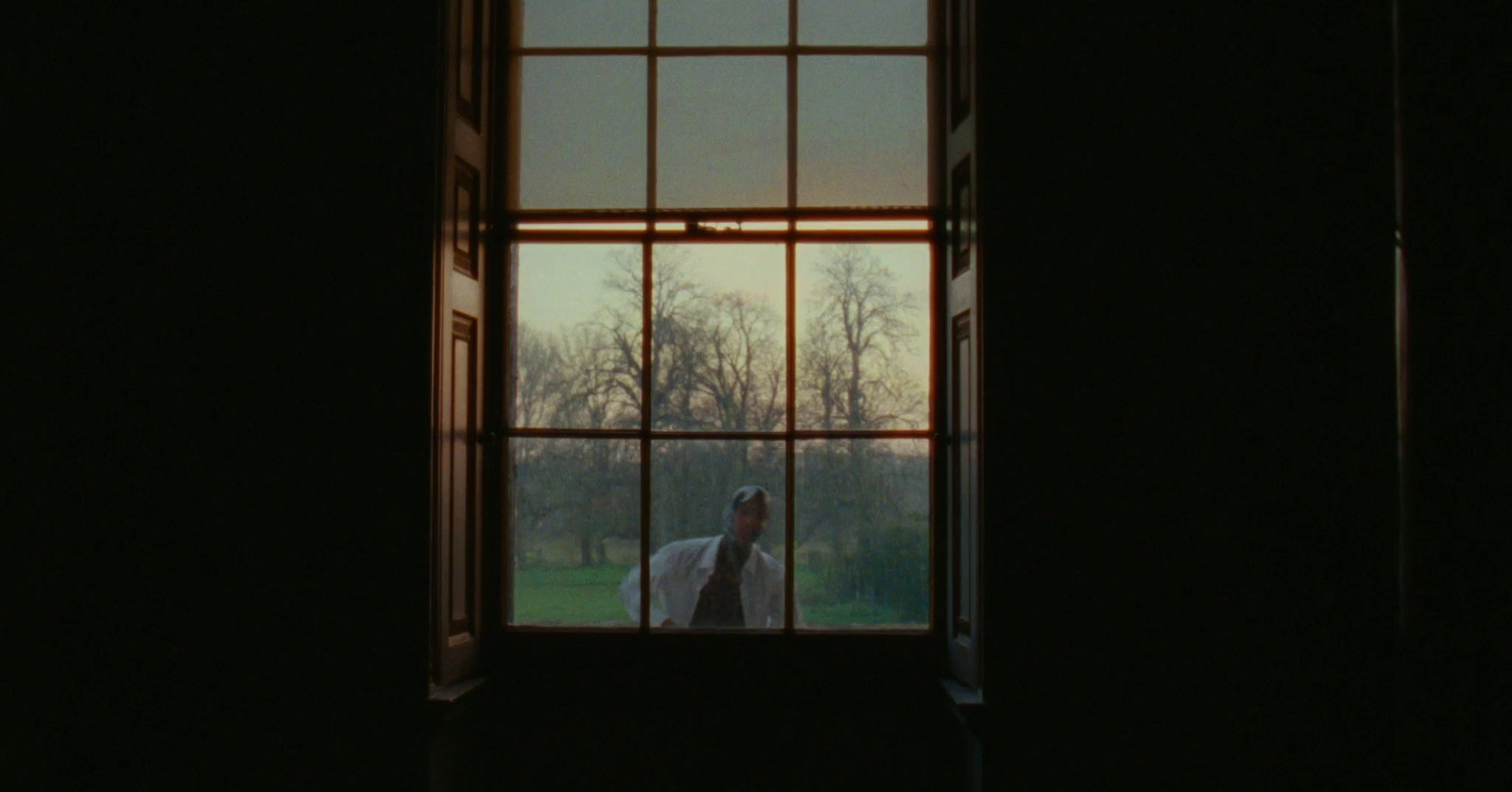 a person standing in front of a window in a dark room