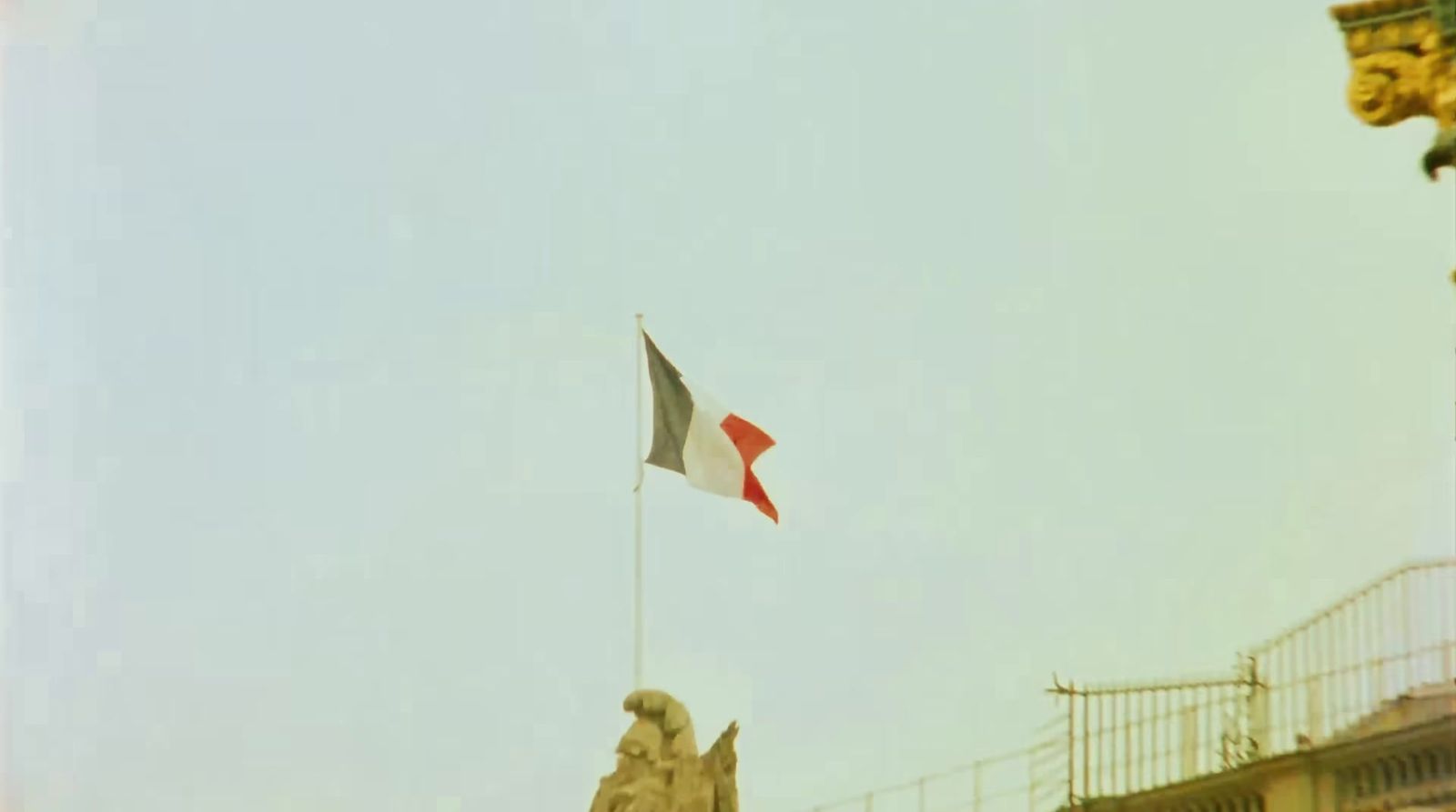 a flag flying in the wind next to a statue