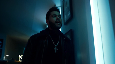 a man in a dark room with a cross on his necklace