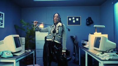 a woman standing in an office holding a stick