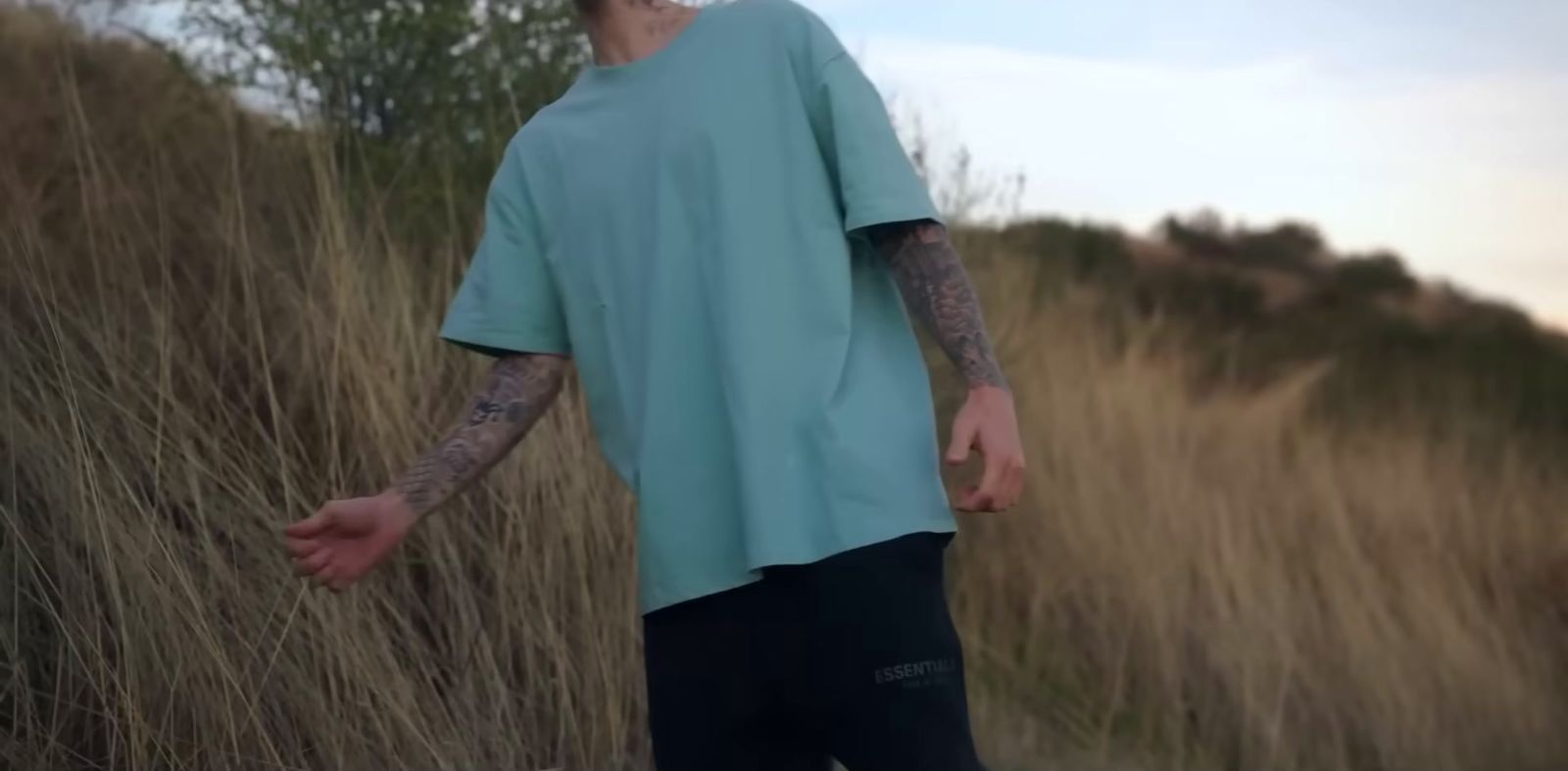 a man with tattoos standing in a field