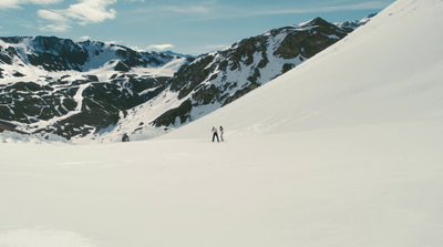 a couple of people standing on top of a snow covered slope