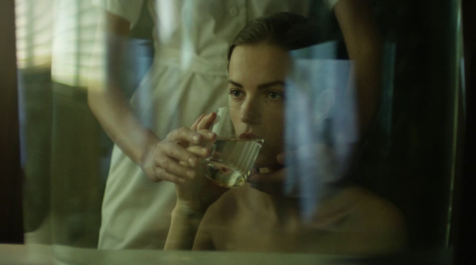 a man drinking from a glass in front of a mirror