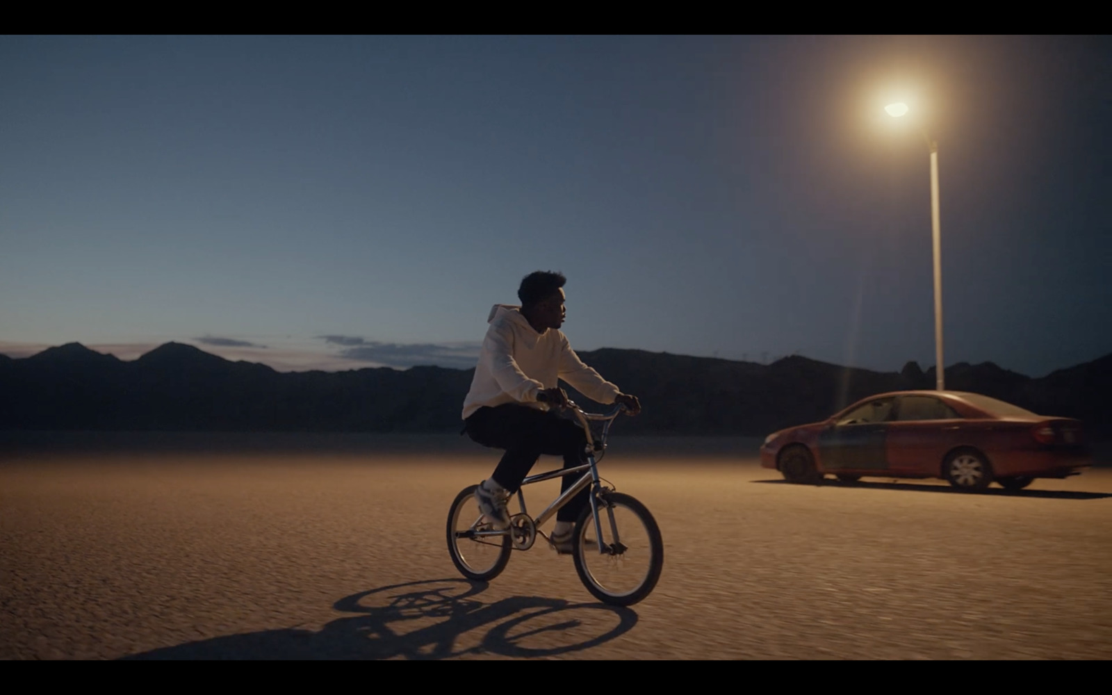 a man riding a bike down a street next to a car