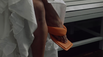 a woman in a white dress holding an orange purse