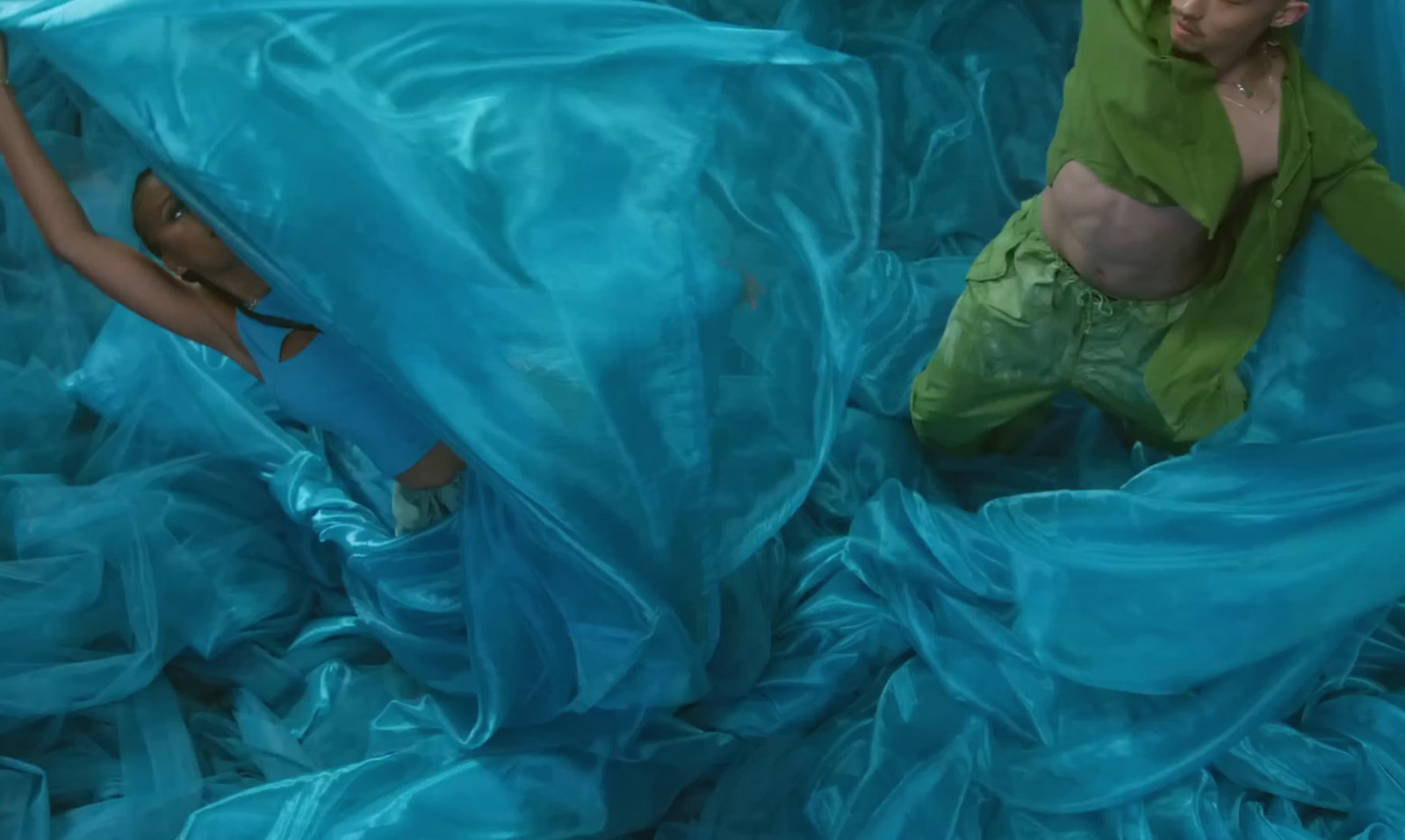 a woman laying on top of a bed covered in blue sheets