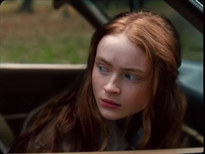 a girl with red hair looking out of a car window