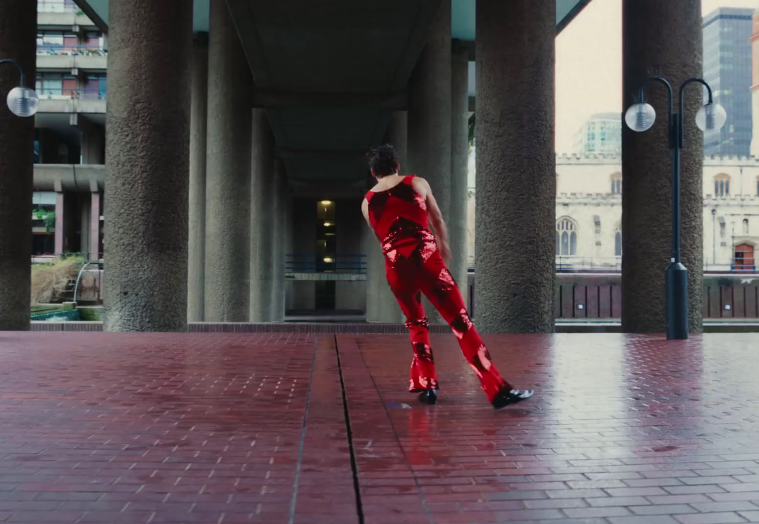 a woman in a red outfit is walking in a courtyard