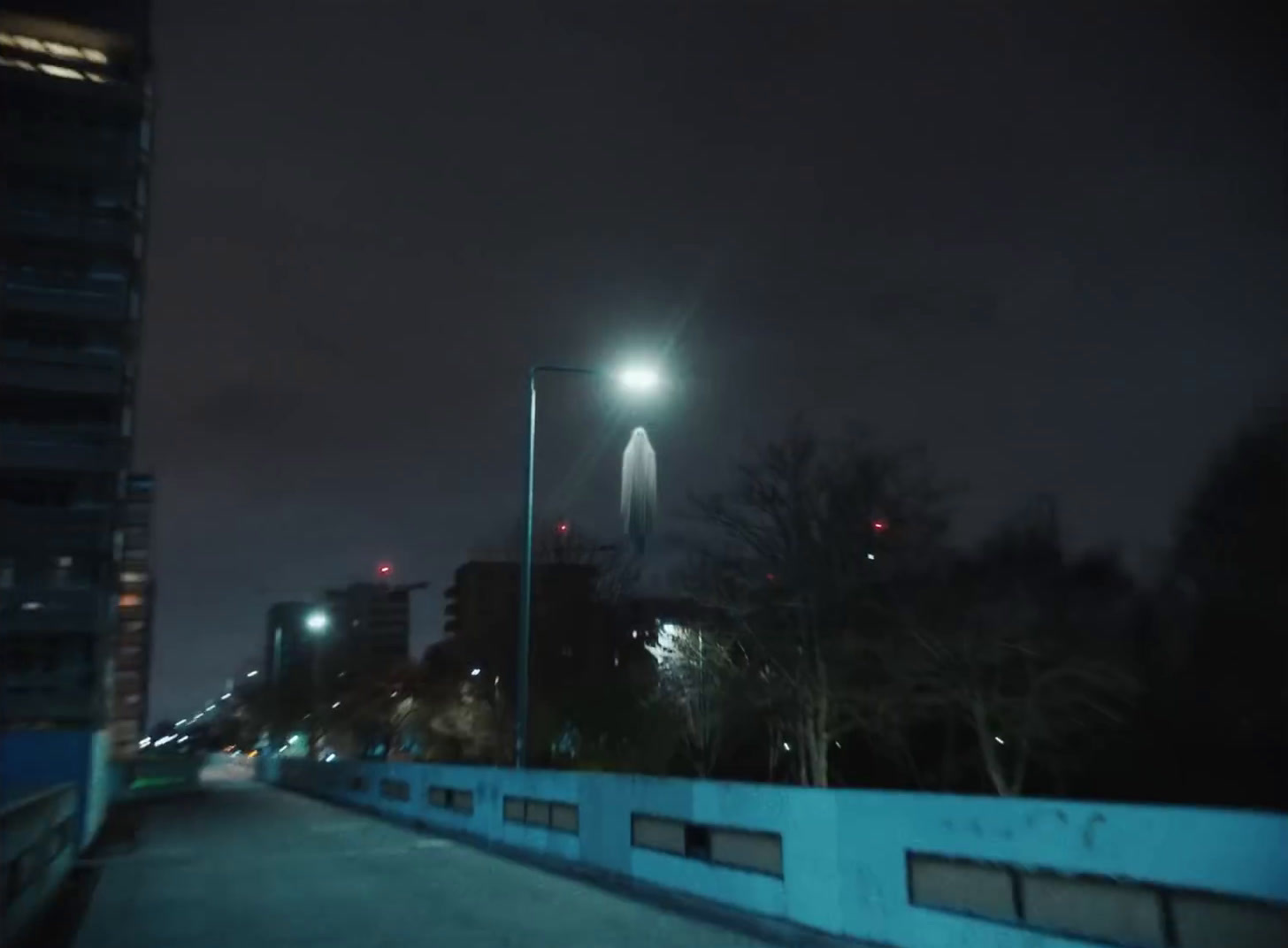 a city street at night with a street light in the distance