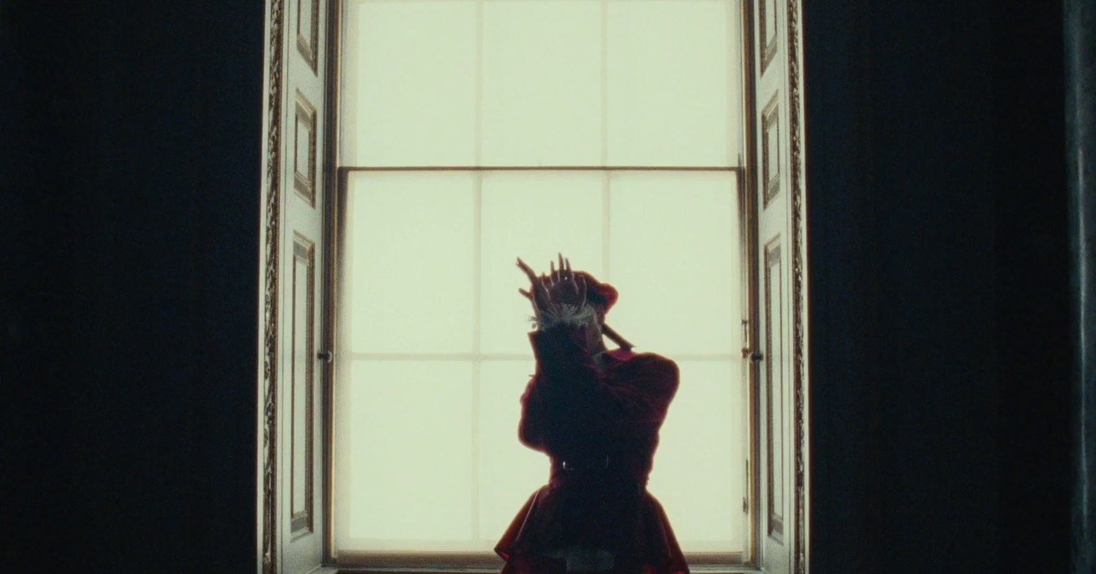 a woman in a red dress standing in front of a window