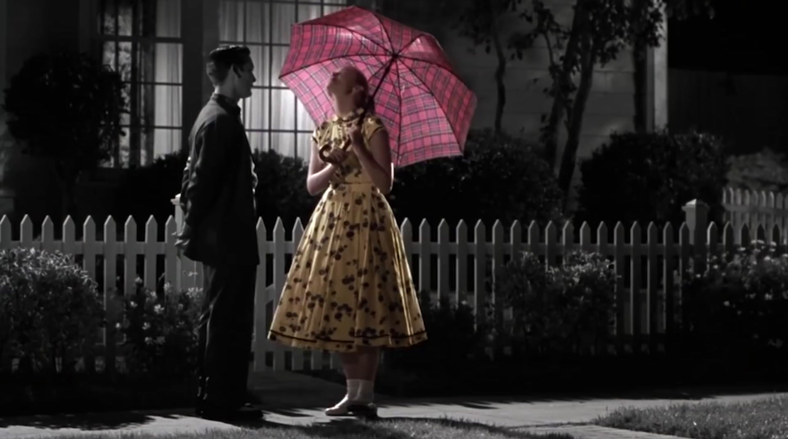 a woman holding a pink umbrella standing next to a man