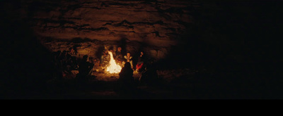 a group of people standing around a fire in a cave