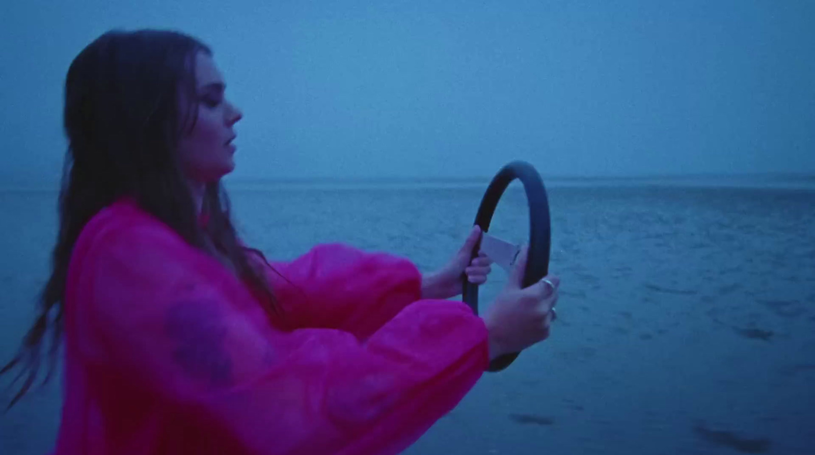 a woman holding a steering wheel on a beach