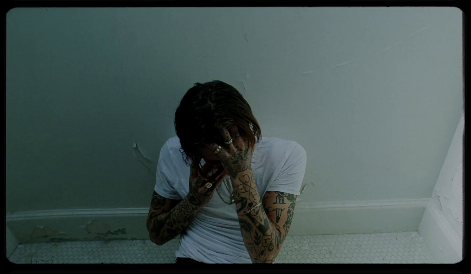 a man with tattoos covering his face standing in front of a wall