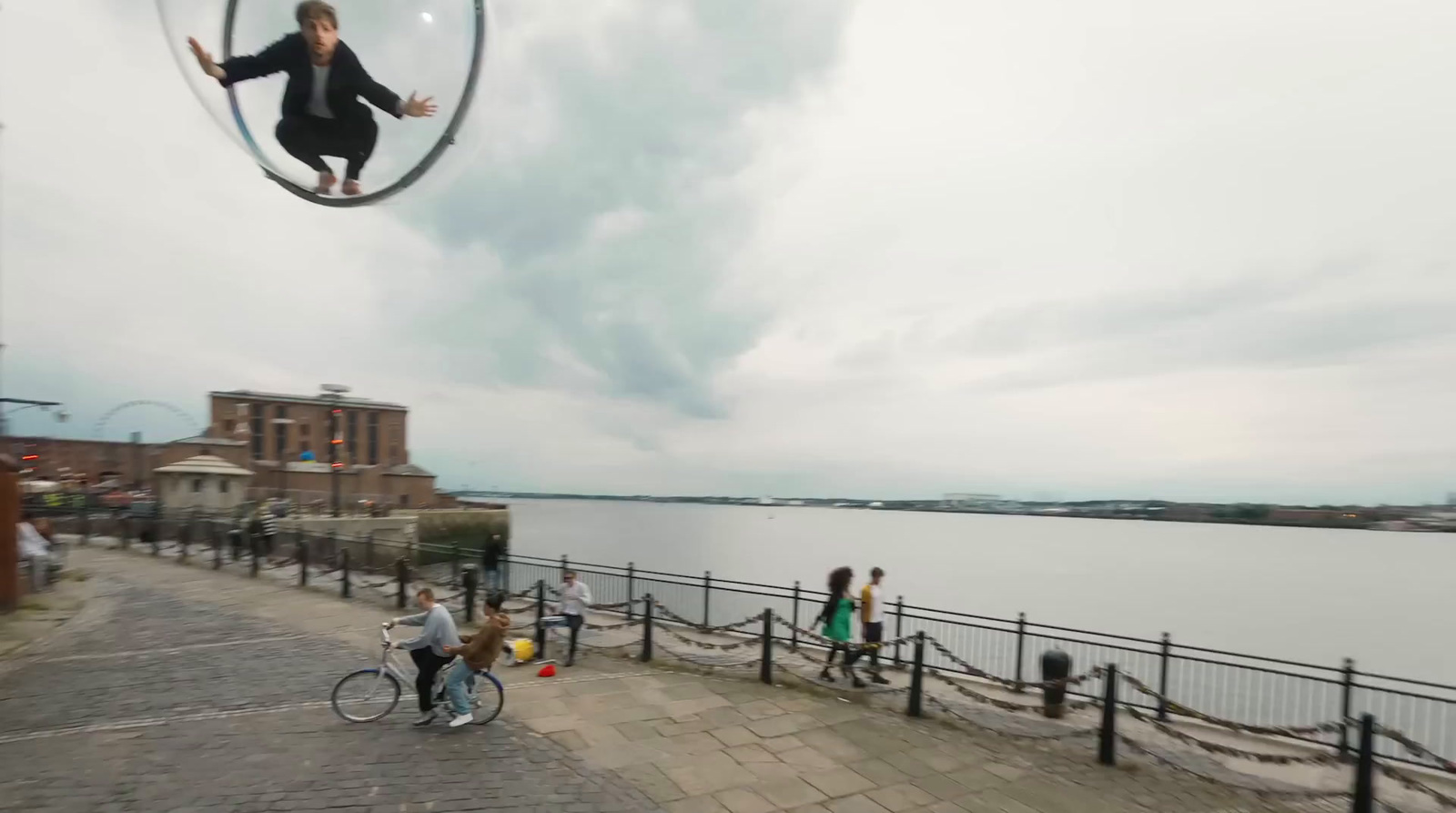 a person riding a bike on a walkway next to a body of water