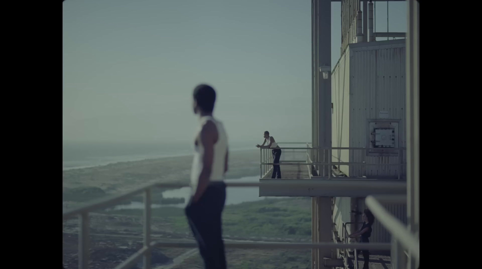 a man standing on top of a balcony next to a tall building