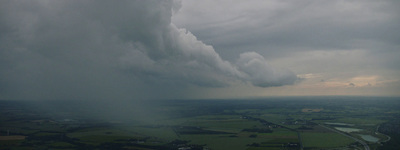 a large cloud is in the sky over a green field