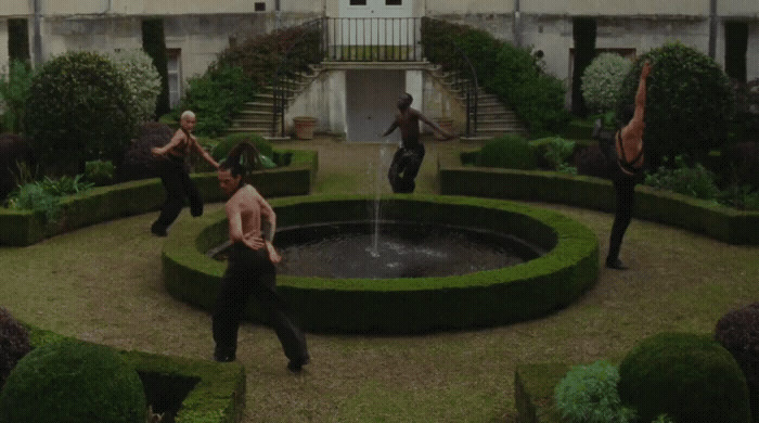 a group of men dancing around a fountain in a courtyard