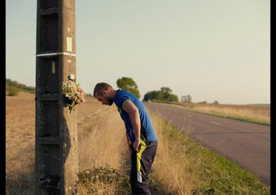 a man leaning against a telephone pole on the side of the road