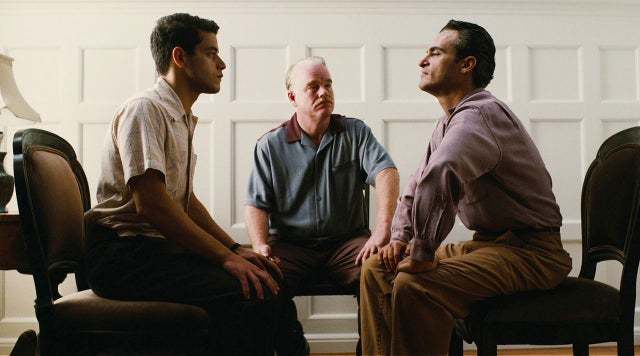 a group of men sitting on top of a wooden chair