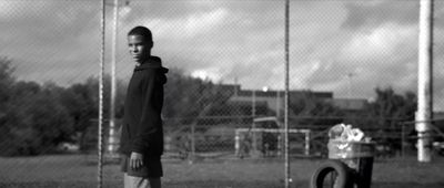 a boy standing in front of a chain link fence