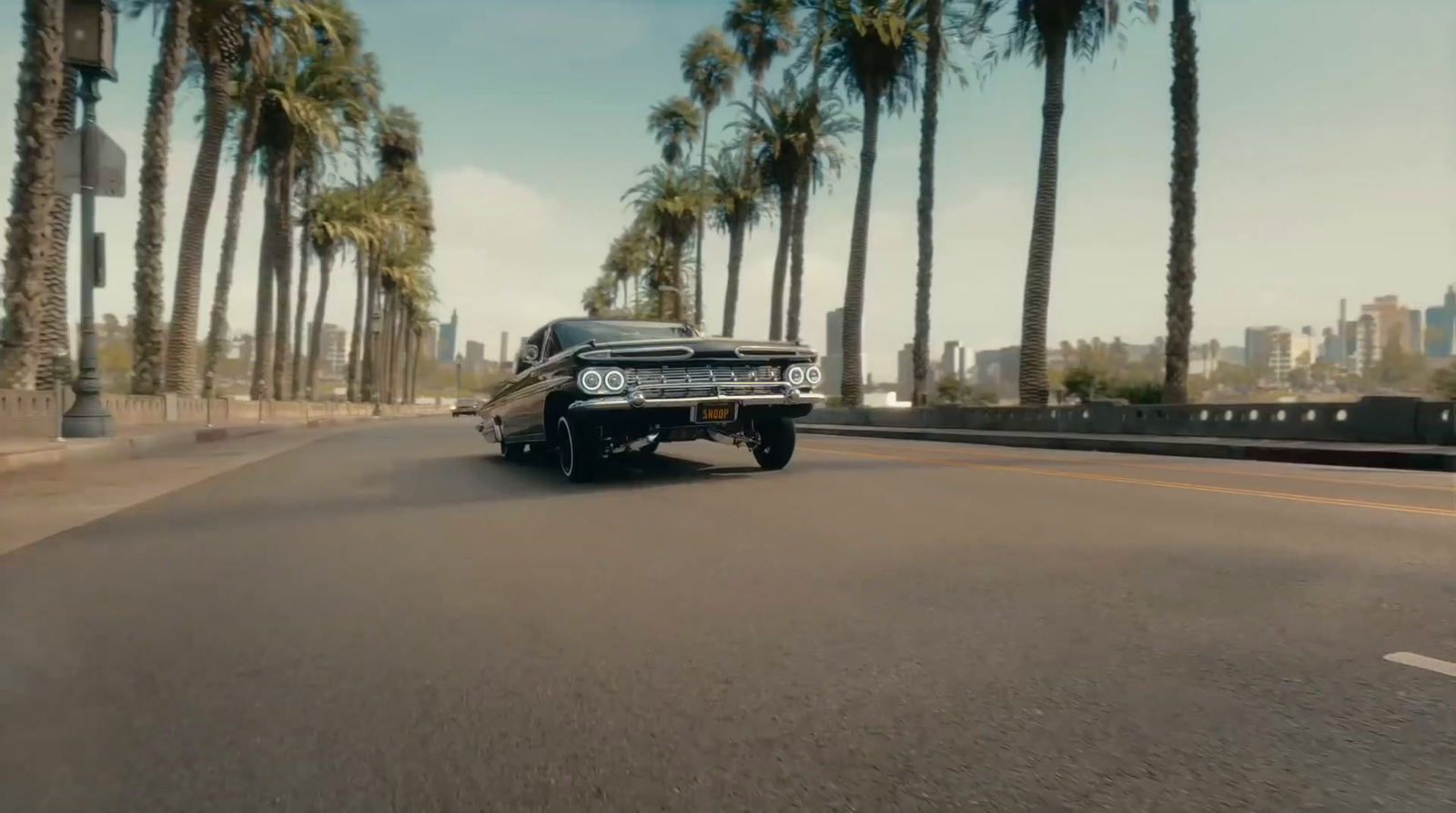 a black car driving down a street next to palm trees