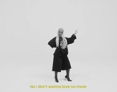 a woman in a black coat and scarf standing in front of a white background