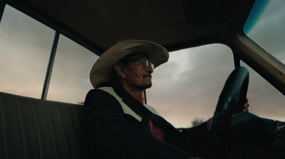 a man in a cowboy hat driving a car