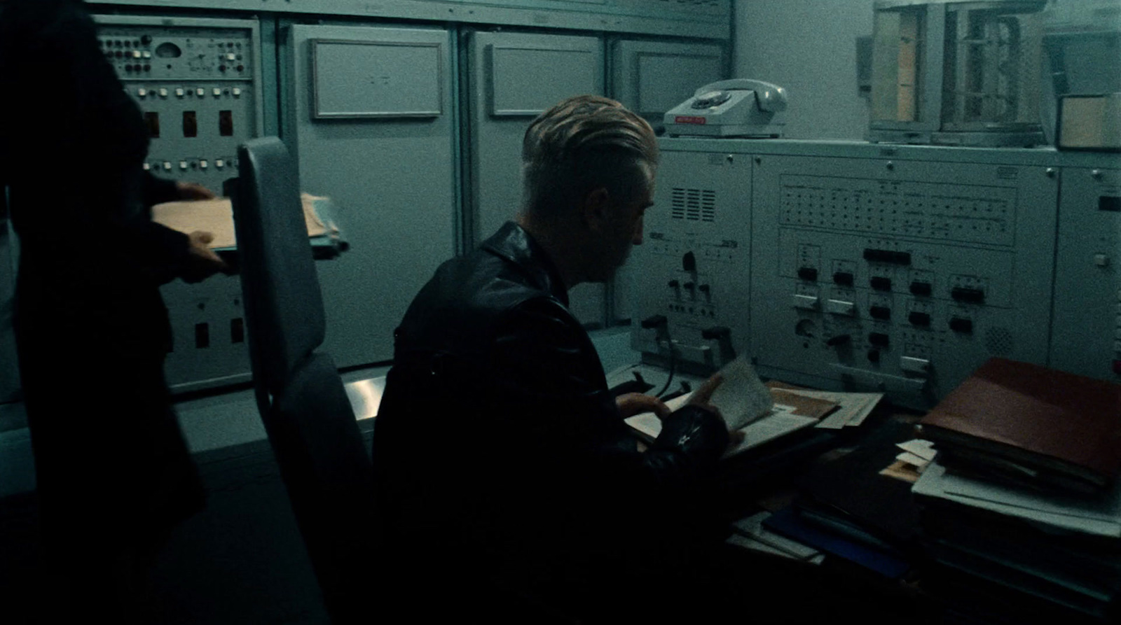 a man sitting at a desk in a control room