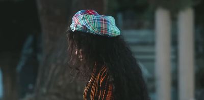 a woman with long hair wearing a plaid hat