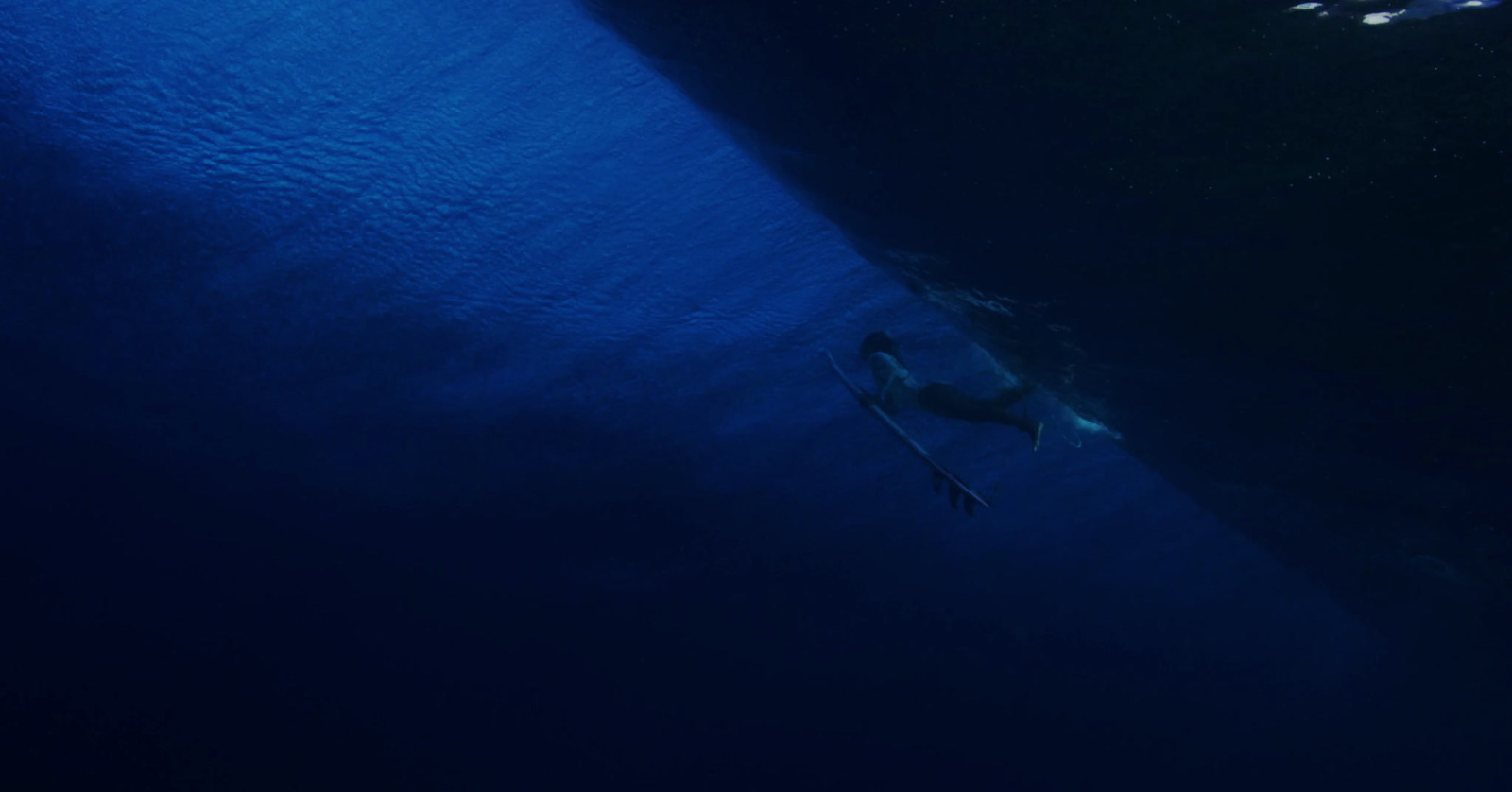 a man swimming in the ocean with a surfboard