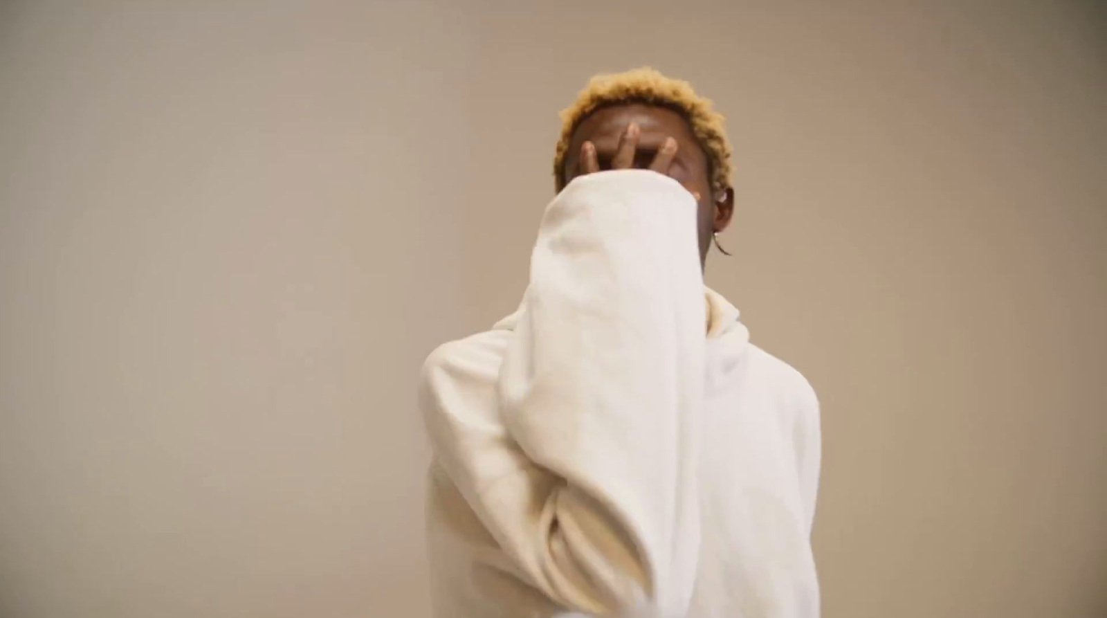 a man covering his face with a white sweatshirt