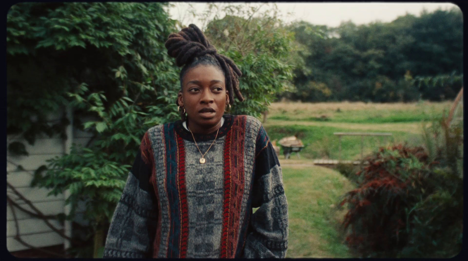 a woman with dreadlocks standing in front of a house