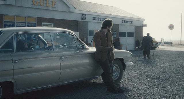 a man standing next to a car in front of a building