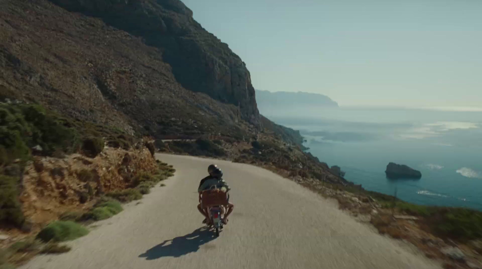 a man riding a bike down a road next to the ocean