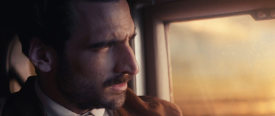 a man in a suit and tie looking out a window