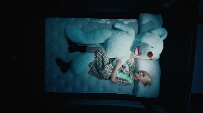 a child laying on a bed with a large teddy bear