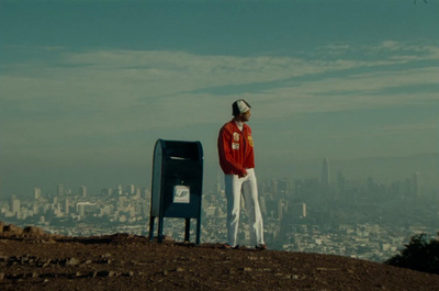 a man standing on top of a hill next to a mailbox