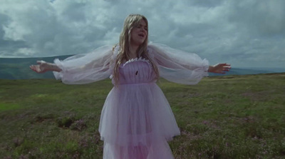 a girl in a dress standing in a field