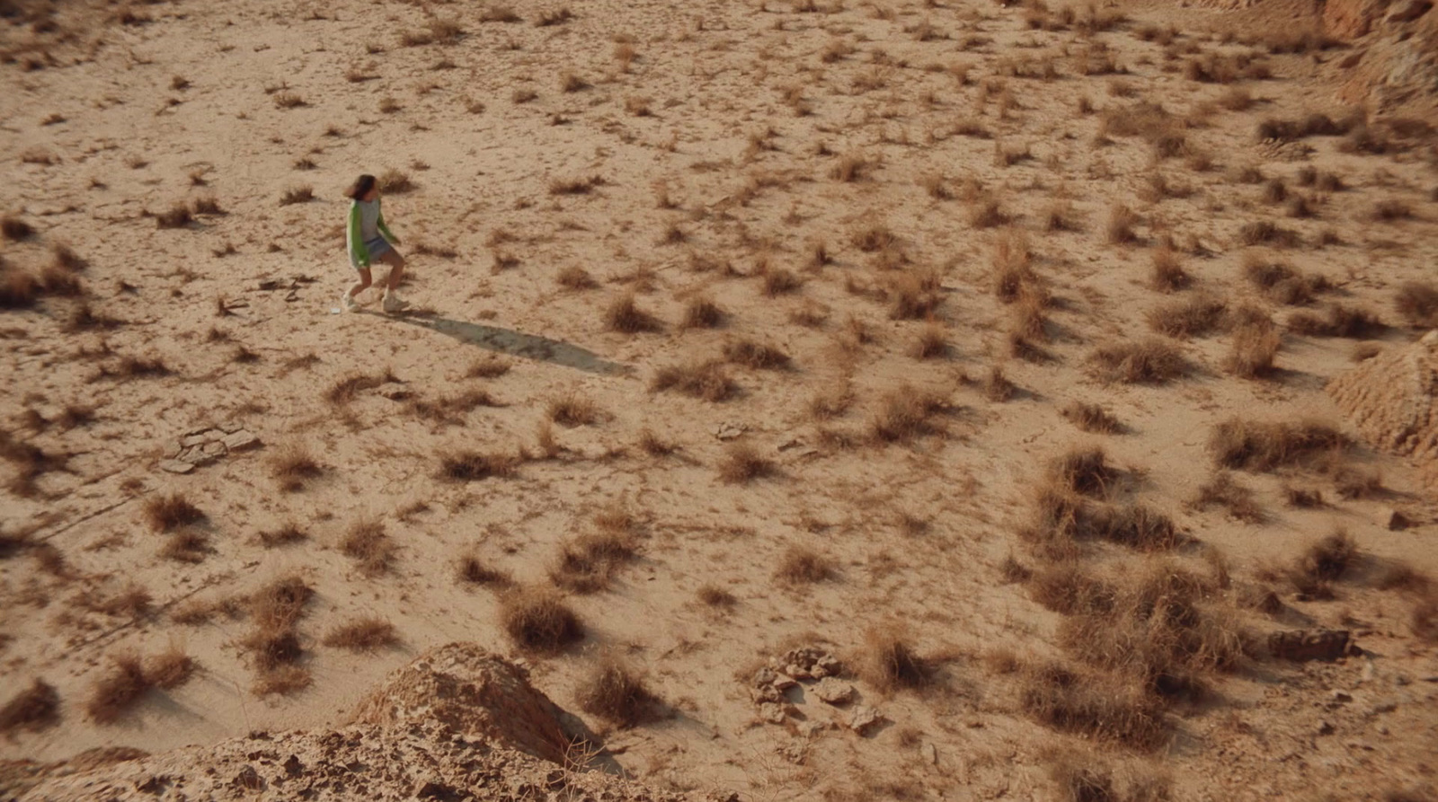 a little girl is flying a kite in the desert