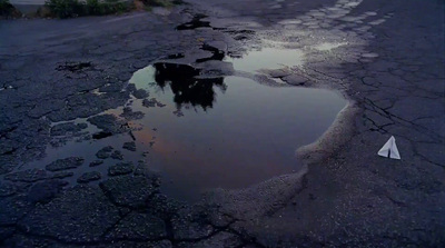 a puddle of water on the side of a road