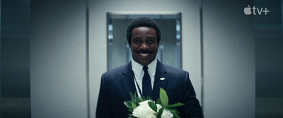 a man in a suit and tie holding a bouquet of flowers