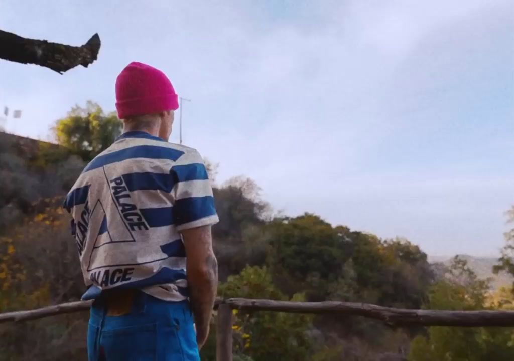 a man wearing a pink hat standing next to a wooden fence