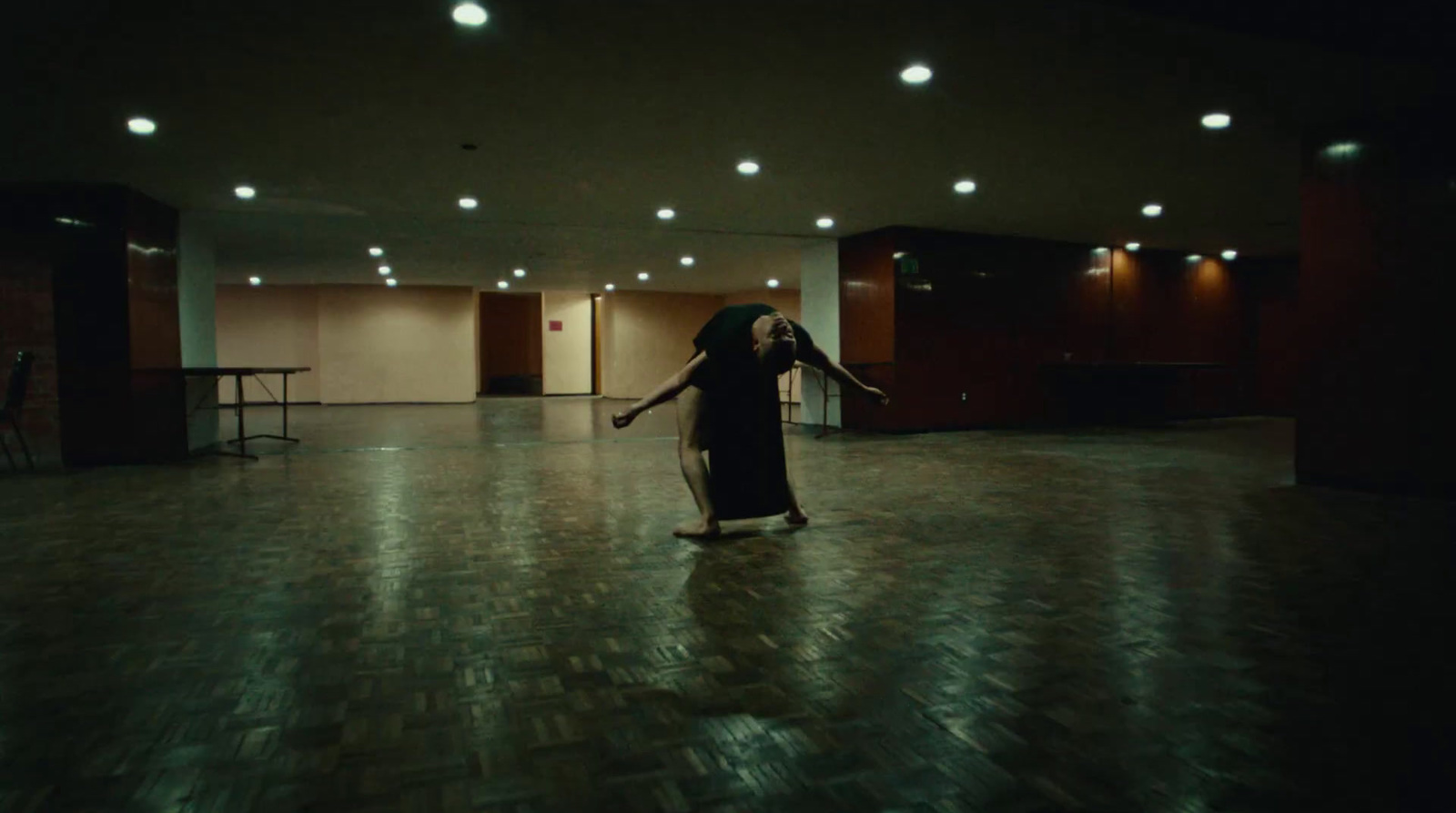 a woman standing in a dark room with her arms outstretched