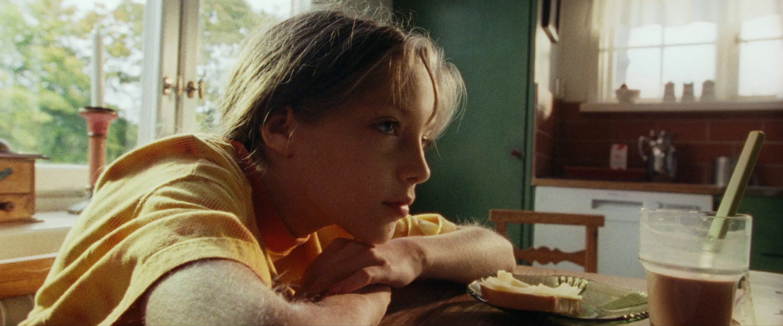 a little girl sitting at a table with a plate of food