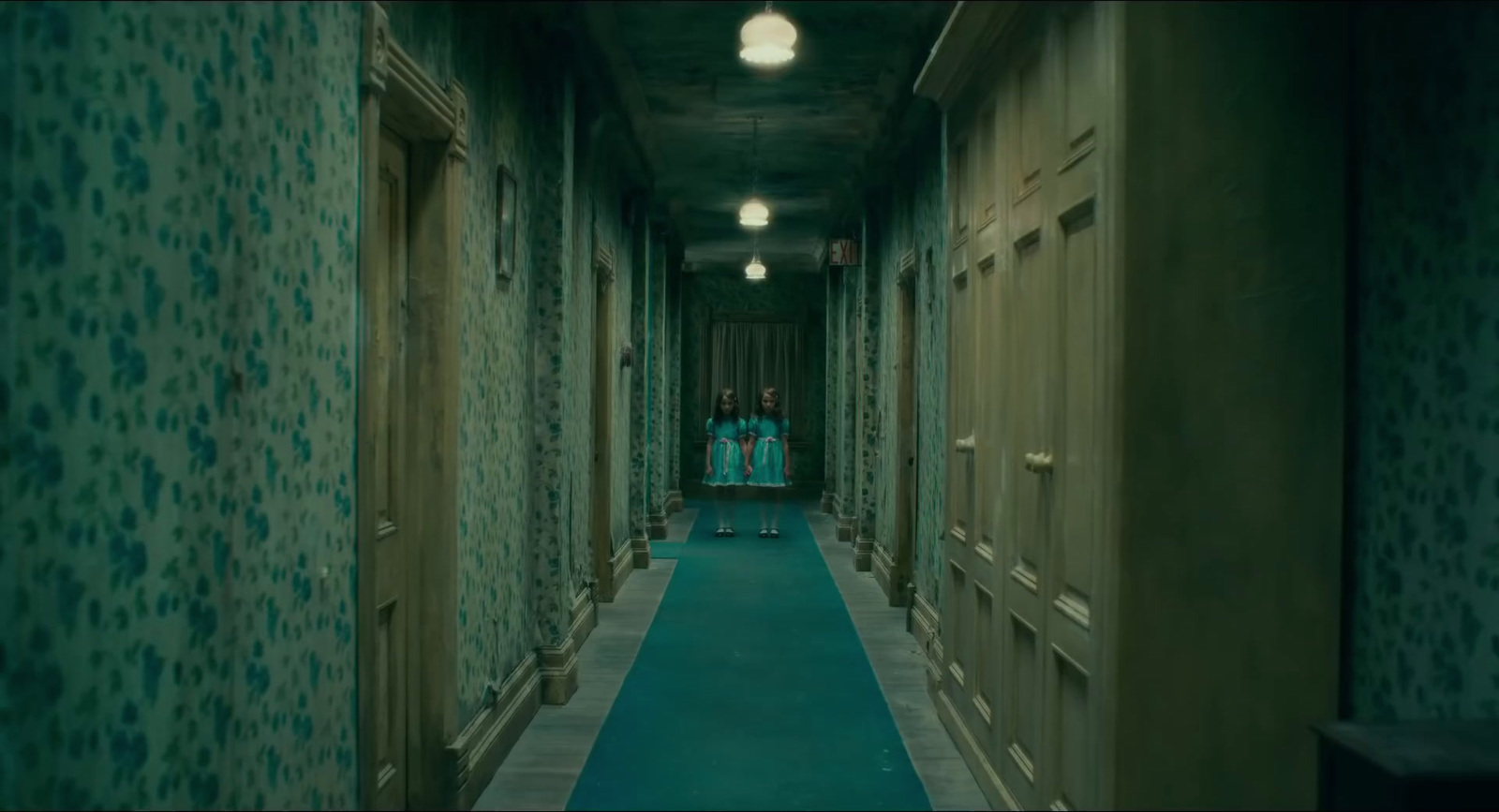 a long hallway with green walls and blue carpet