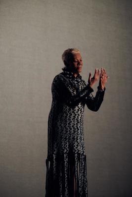 a woman in a black and white dress is holding her hands together