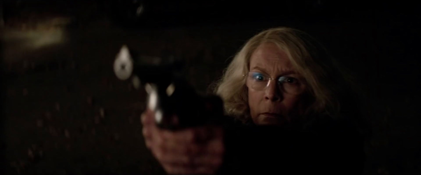 a woman holding a gun in a dark room