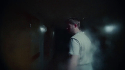 a man in a white shirt standing in a dark room